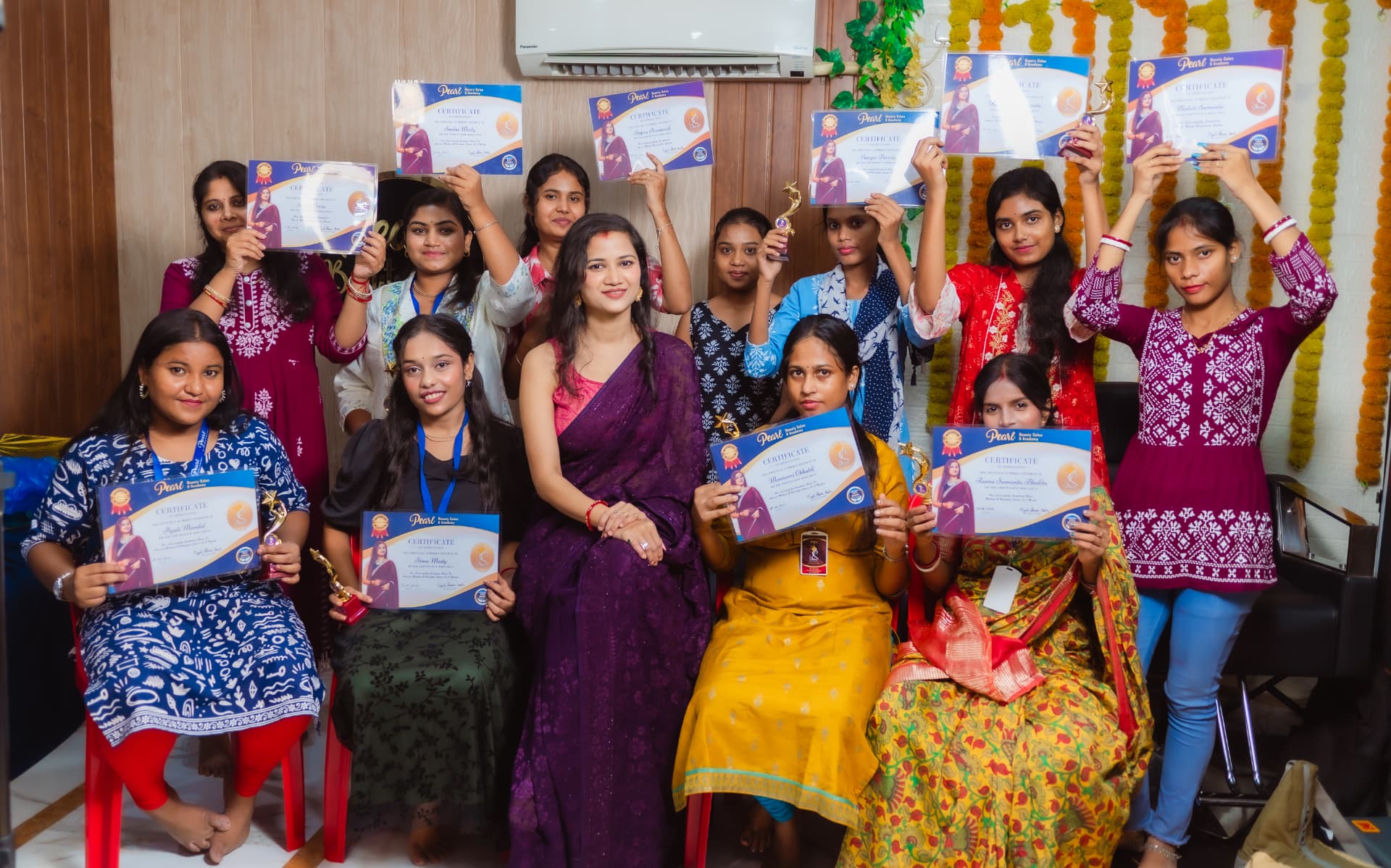 Group of Pearl Beauty Salon & Academy students proudly holding their certificates and trophies together